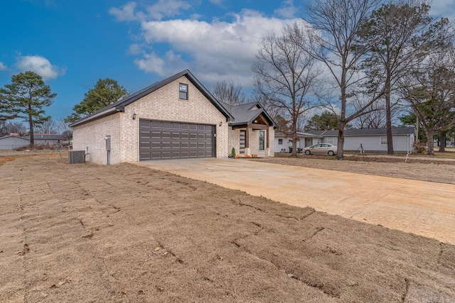 single story home featuring concrete driveway, brick siding, an attached garage, and central air condition unit