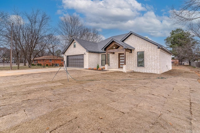 view of front of house featuring driveway, brick siding, and an attached garage