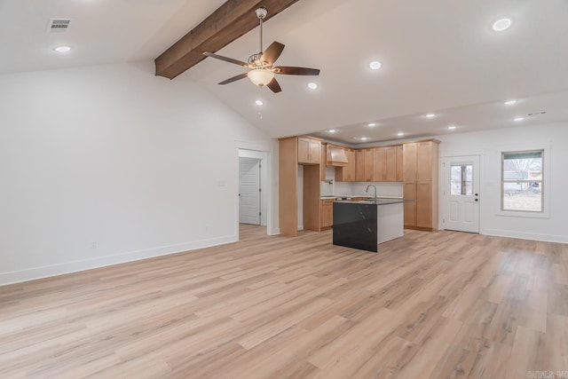 kitchen with a center island with sink, ceiling fan, open floor plan, vaulted ceiling with beams, and light wood-type flooring