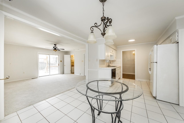 kitchen featuring light carpet, light tile patterned floors, ornamental molding, freestanding refrigerator, and light countertops