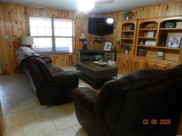 living area featuring light tile patterned floors, ceiling fan, and wooden walls