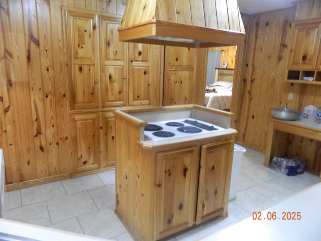 kitchen with white electric cooktop, light tile patterned floors, wooden walls, and a kitchen island