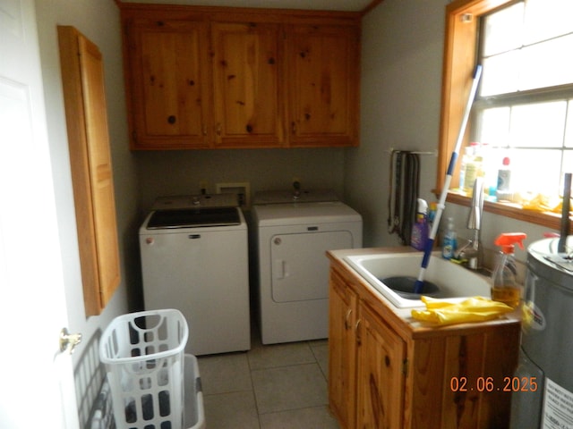 clothes washing area with a sink, light tile patterned flooring, washing machine and clothes dryer, and cabinet space