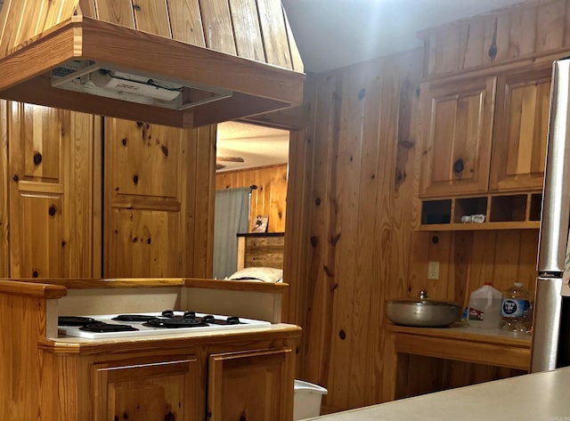 interior space with wood walls, white stovetop, and freestanding refrigerator