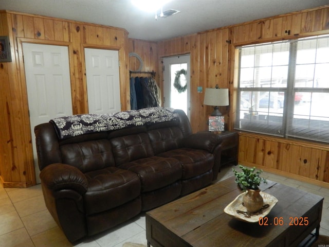 living room with visible vents, wooden walls, and light tile patterned floors