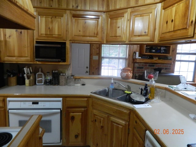 kitchen featuring white oven, light countertops, and a sink