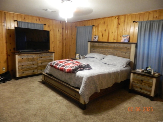 carpeted bedroom with wooden walls and visible vents