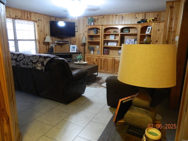 living room with a ceiling fan, light tile patterned flooring, and wooden walls