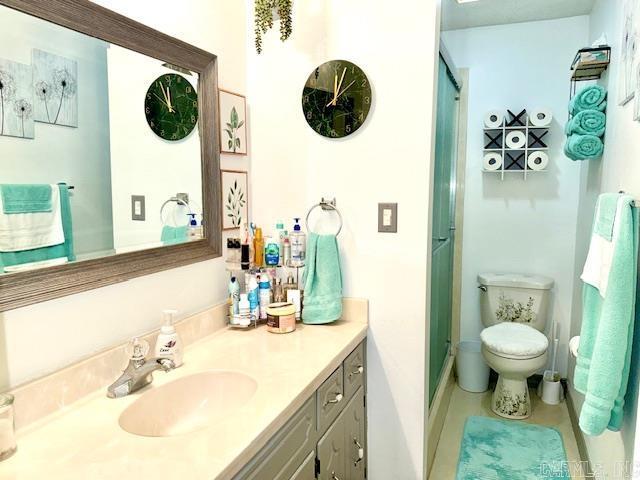 bathroom featuring toilet, an enclosed shower, and vanity