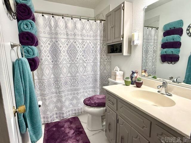 bathroom featuring a textured ceiling, curtained shower, toilet, vanity, and marble finish floor