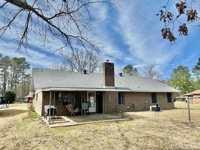 back of property featuring a patio, brick siding, a chimney, and central air condition unit