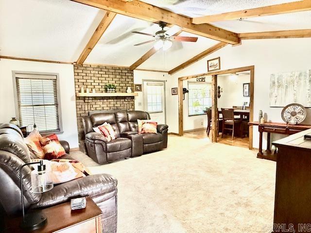 carpeted living room featuring vaulted ceiling with beams, ceiling fan, and a brick fireplace