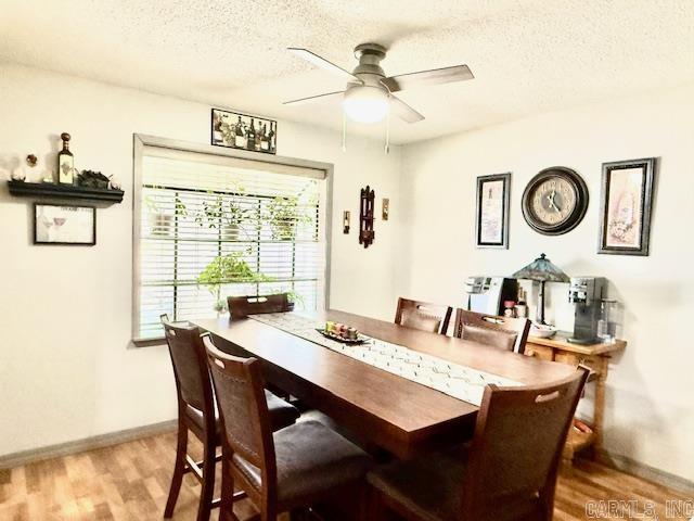 dining area with a textured ceiling, ceiling fan, baseboards, and light wood-style floors