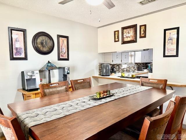 dining area with a ceiling fan, visible vents, and a textured ceiling