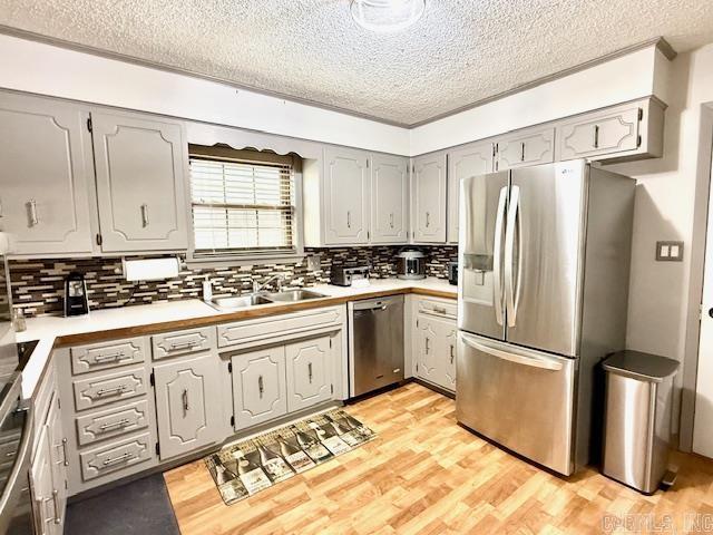 kitchen featuring a sink, light countertops, appliances with stainless steel finishes, gray cabinets, and light wood finished floors