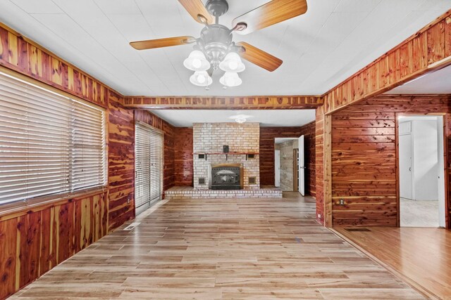 1580 Ridge Rd, El Paso, AR 72045 - unfurnished living room featuring wood walls, a brick fireplace, a ceiling fan, and light wood-style floors