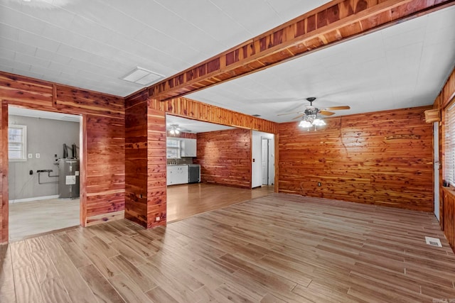 1580 Ridge Rd, El Paso, AR 72045 - spare room with wood walls, a ceiling fan, visible vents, water heater, and light wood-style floors
