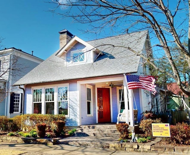 view of front of home with a shingled roof, a chimney, and a porch