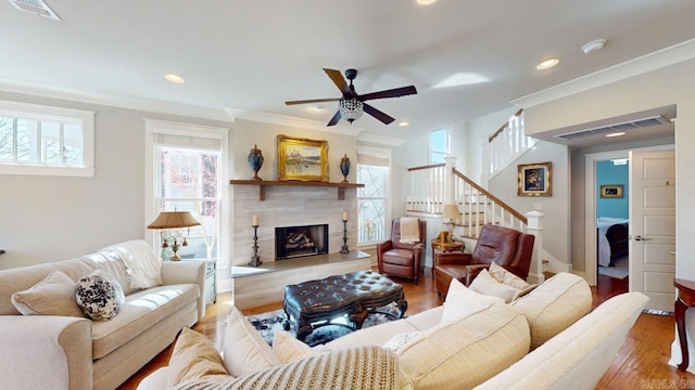 living room featuring ornamental molding, a wealth of natural light, visible vents, and wood finished floors