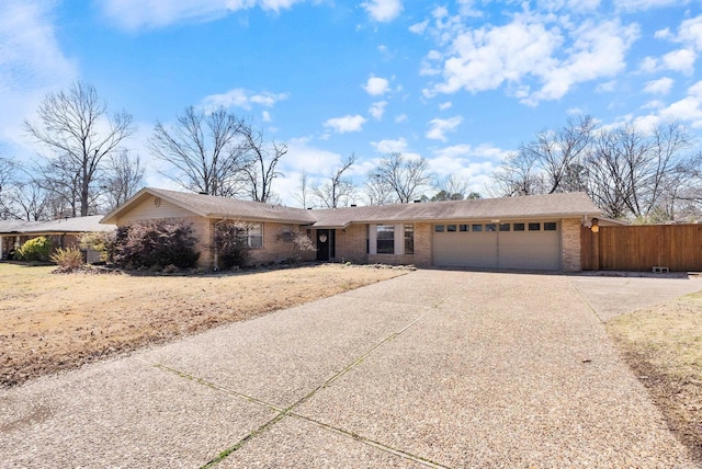 ranch-style home with driveway, an attached garage, fence, and brick siding