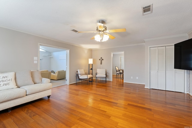 unfurnished living room featuring crown molding, light wood-type flooring, visible vents, and ceiling fan