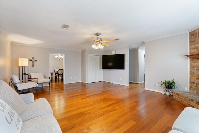 living area featuring ceiling fan with notable chandelier, light wood finished floors, a fireplace, and visible vents