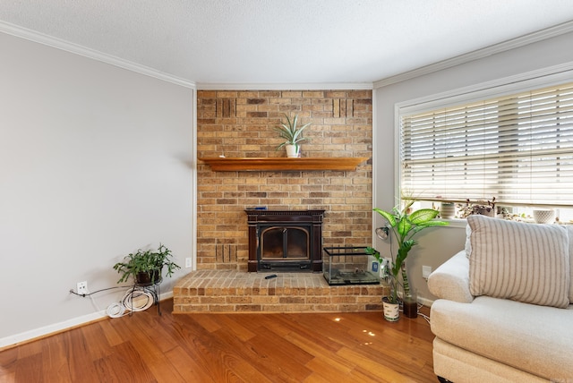 living area with a textured ceiling, ornamental molding, wood finished floors, and baseboards