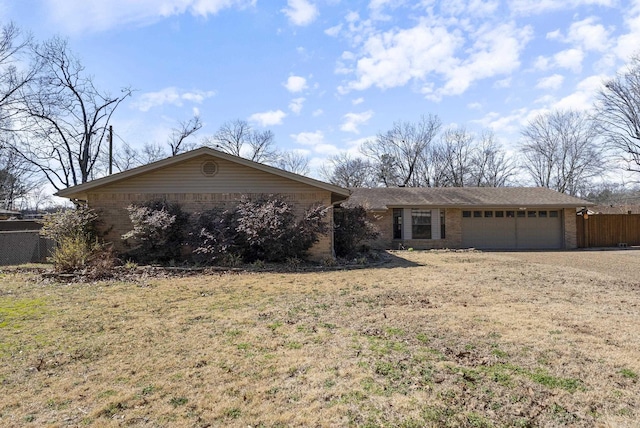 single story home featuring dirt driveway, brick siding, an attached garage, and fence