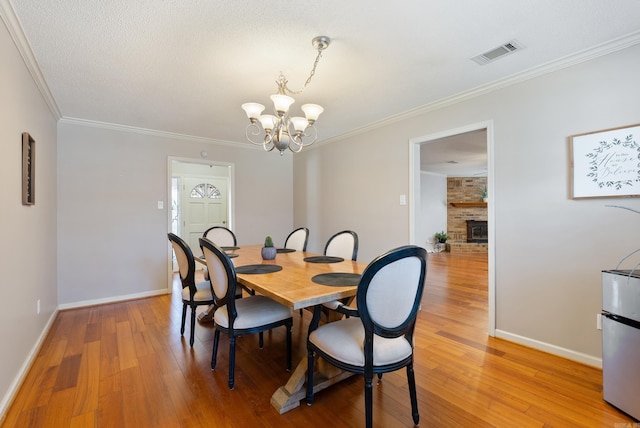 dining space featuring light wood-style floors, visible vents, a chandelier, and crown molding