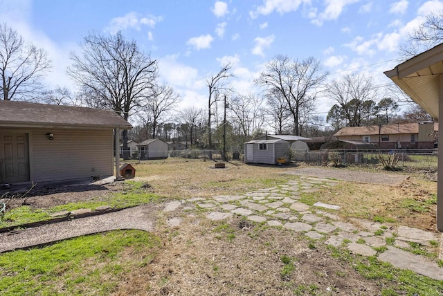 view of yard featuring a storage unit, fence, and an outbuilding