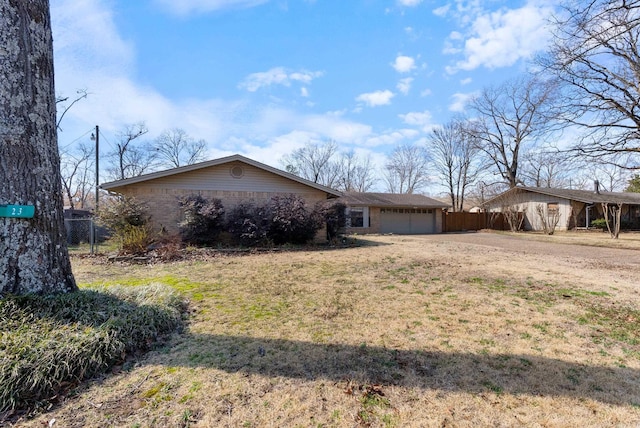 view of front of home featuring brick siding, fence, driveway, and an attached garage