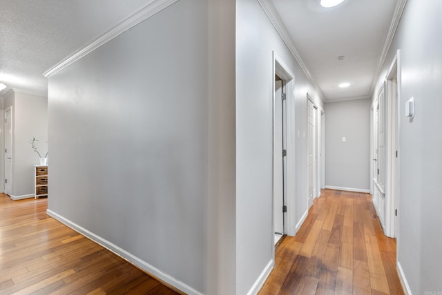 corridor with baseboards, light wood-style floors, and crown molding