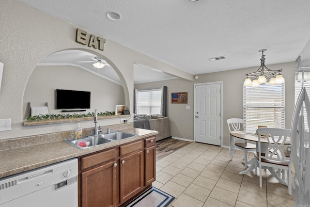 kitchen featuring brown cabinets, lofted ceiling, visible vents, a sink, and dishwasher