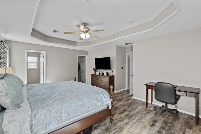 bedroom with baseboards, visible vents, a ceiling fan, a raised ceiling, and wood finished floors