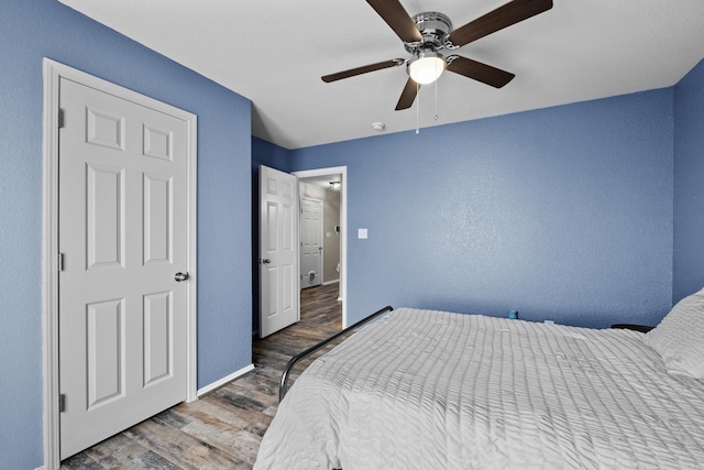 bedroom featuring ceiling fan, baseboards, and wood finished floors