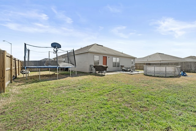 rear view of house with a patio, a fenced backyard, a pool, a yard, and a trampoline