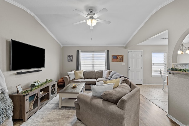 living area featuring lofted ceiling, a wealth of natural light, ceiling fan, and crown molding