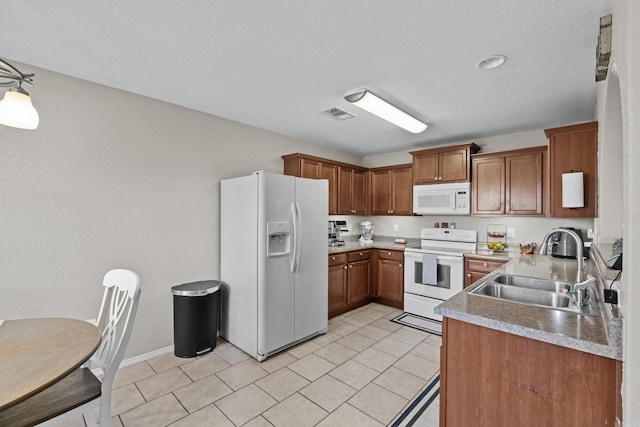 kitchen featuring white appliances, brown cabinets, light countertops, a sink, and light tile patterned flooring