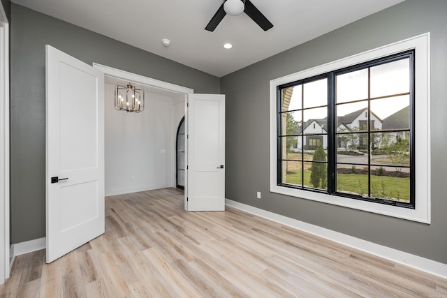 unfurnished bedroom featuring recessed lighting, light wood-style flooring, baseboards, and ceiling fan with notable chandelier