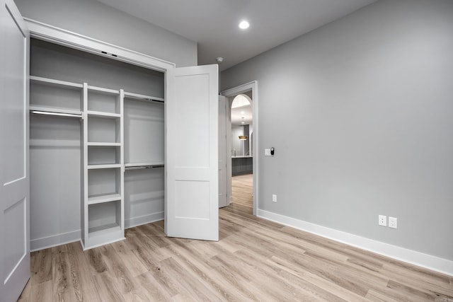 unfurnished bedroom with recessed lighting, a closet, baseboards, and wood finished floors