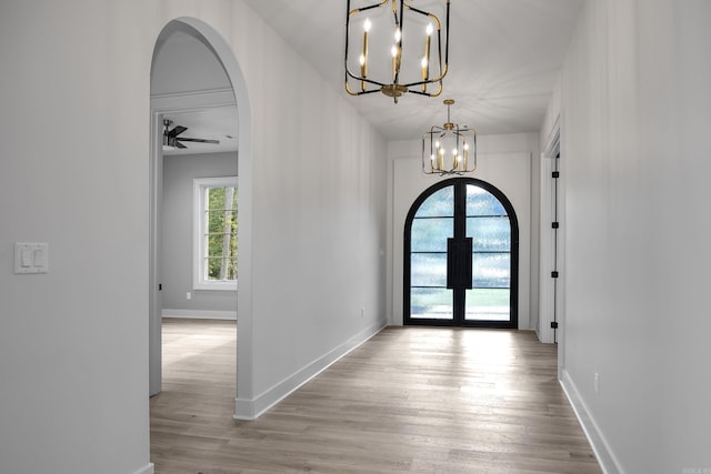 entrance foyer with arched walkways, french doors, baseboards, and wood finished floors