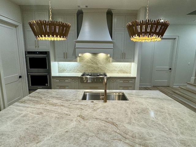 kitchen with premium range hood, stainless steel double oven, a sink, and decorative backsplash