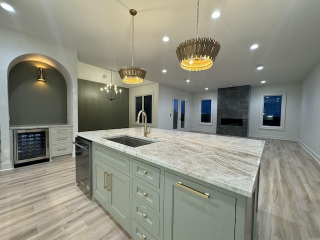 kitchen with light stone counters, recessed lighting, beverage cooler, a sink, and dishwasher