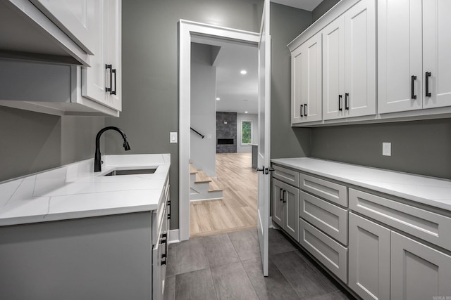 kitchen featuring recessed lighting, gray cabinets, a sink, ventilation hood, and wood finished floors