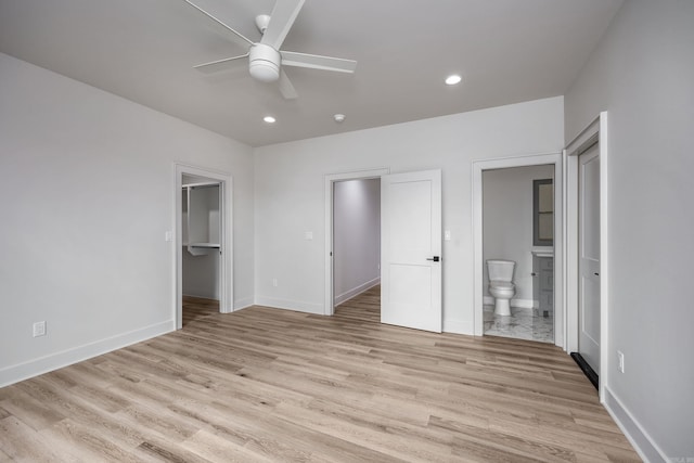 unfurnished bedroom with a walk in closet, recessed lighting, connected bathroom, light wood-type flooring, and baseboards