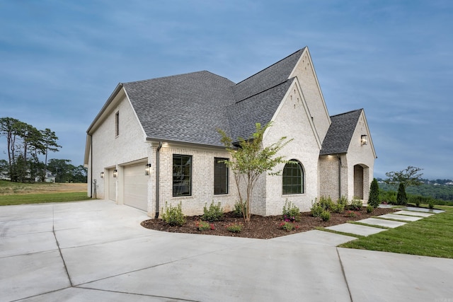 view of home's exterior with driveway, a shingled roof, a garage, and brick siding