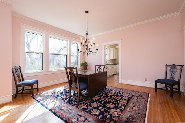 dining area featuring a chandelier, light wood-type flooring, ornamental molding, and baseboards