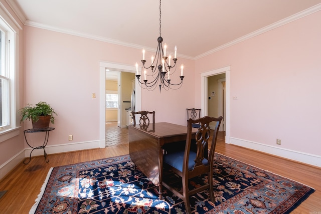 dining space with ornamental molding, an inviting chandelier, baseboards, and wood finished floors