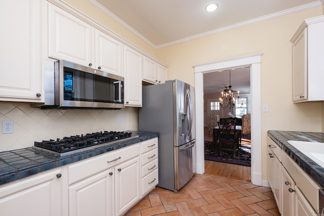 kitchen featuring stainless steel appliances, white cabinetry, ornamental molding, and decorative backsplash