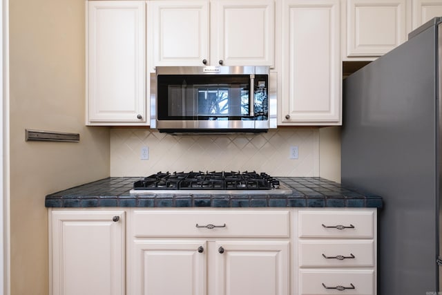 kitchen featuring appliances with stainless steel finishes, white cabinetry, and decorative backsplash